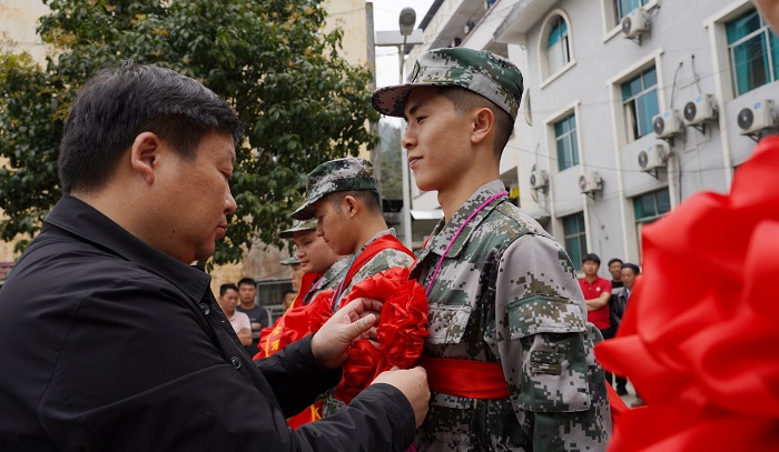 2022年3月14日，在贵州省黔东南苗族侗族自治州从江县停洞镇，工作人员正在为入伍新兵佩戴胸花和整理绶带。 (1)