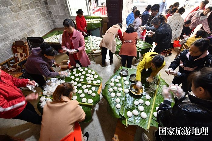 图8：12月2日，在广西河池市大化瑶族自治县仁良村，村民们和游客在体验做手工糍粑。（谭凯兴 摄）